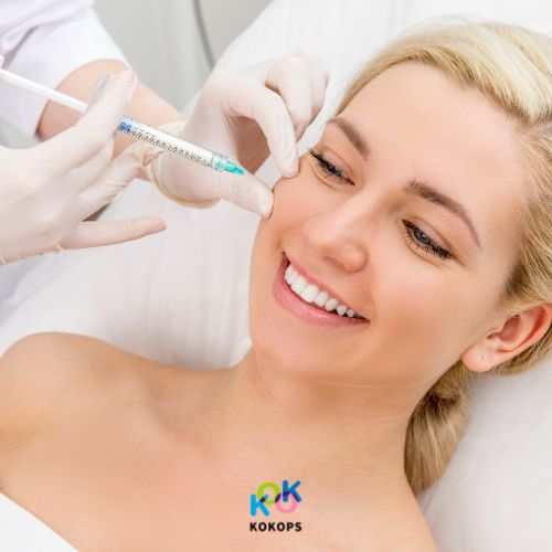 A smiling blonde woman receiving a facial fat dissolving injection at a cosmetic clinic in Seoul, aiming for a V-line.